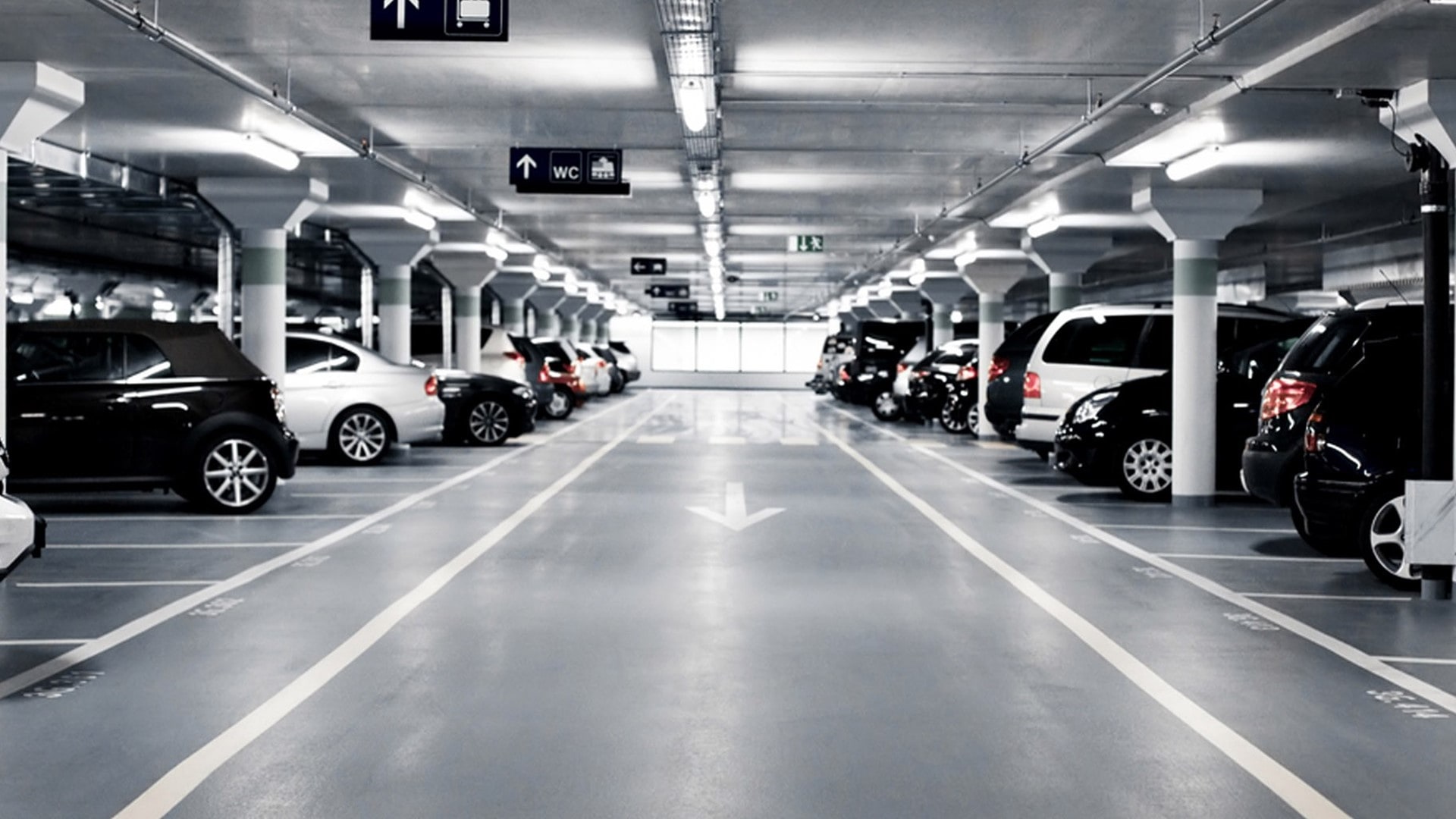 a dark parking lot with cars parked on the left and right side